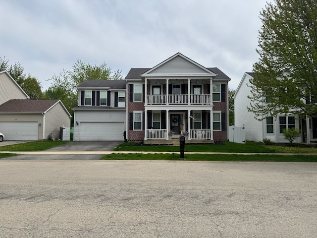neoclassical home with aphalt driveway, a porch, brick siding, and a balcony