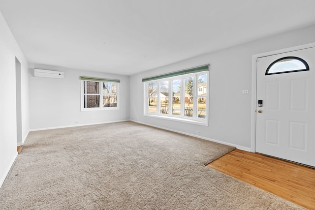 foyer entrance featuring carpet floors, a wall unit AC, and baseboards