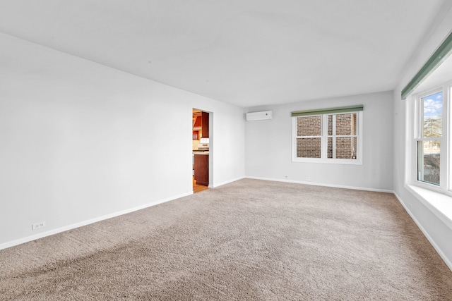 spare room featuring carpet, a wall unit AC, and baseboards