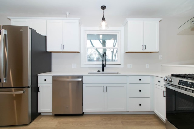 kitchen with light countertops, appliances with stainless steel finishes, a sink, and white cabinets