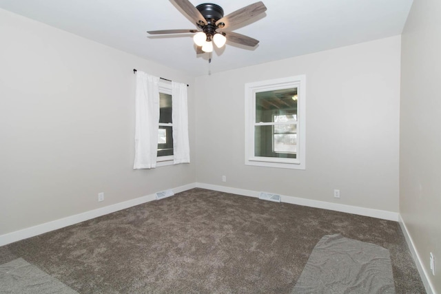 empty room featuring ceiling fan, baseboards, visible vents, and dark carpet