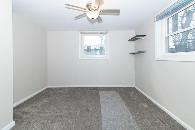 carpeted empty room with a healthy amount of sunlight, ceiling fan, and baseboards