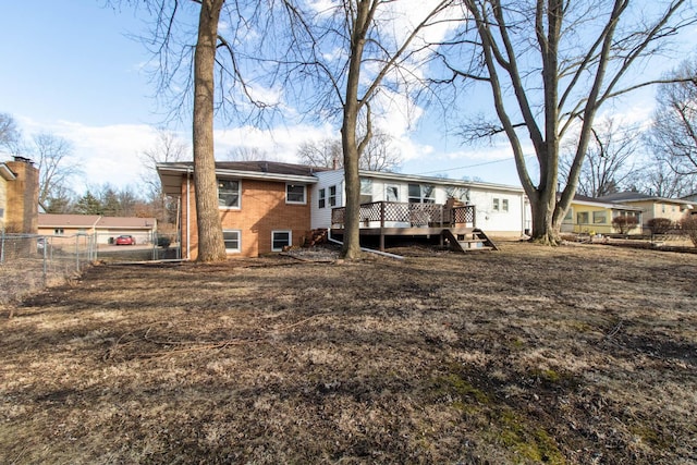 back of property with a wooden deck, fence, and brick siding