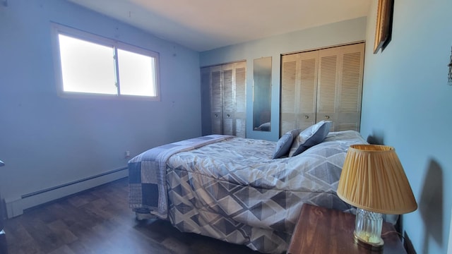 bedroom featuring a baseboard heating unit, wood finished floors, and two closets