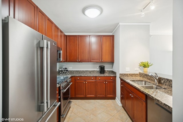 kitchen with premium appliances, crown molding, stone counters, a sink, and light tile patterned flooring