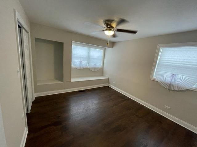 unfurnished bedroom featuring ceiling fan, a closet, baseboards, and dark wood-style flooring