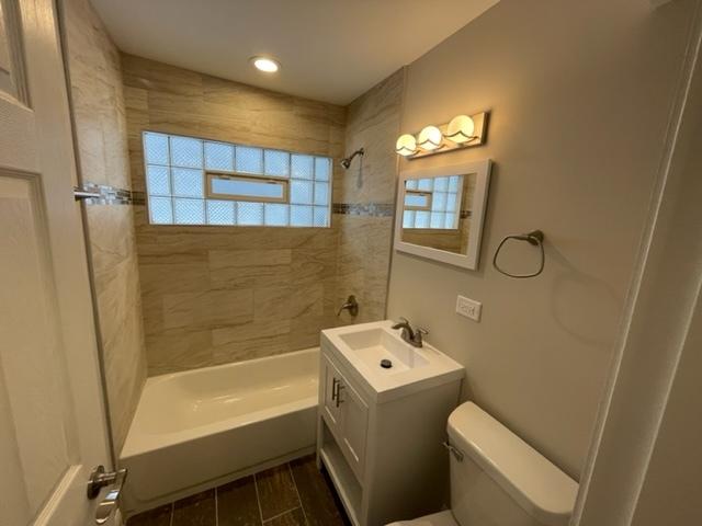 full bathroom with wood tiled floor, shower / bath combination, vanity, and toilet