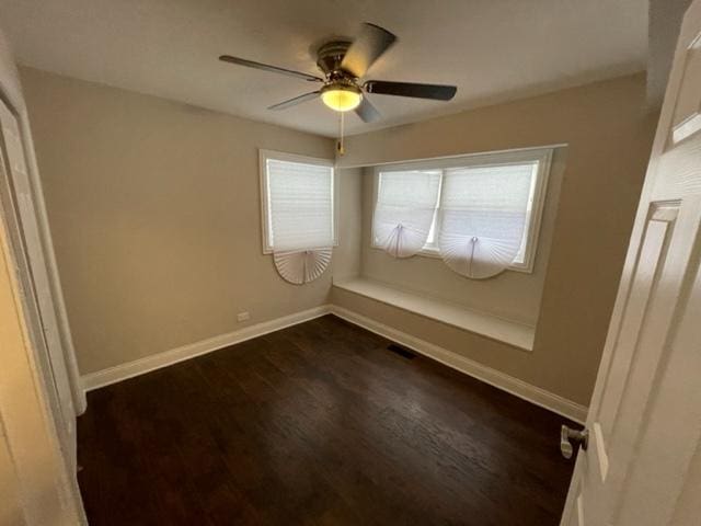 empty room with ceiling fan, visible vents, baseboards, and dark wood-type flooring