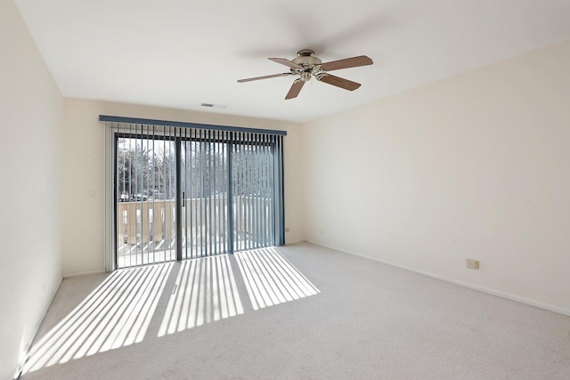 carpeted empty room featuring ceiling fan, visible vents, and baseboards