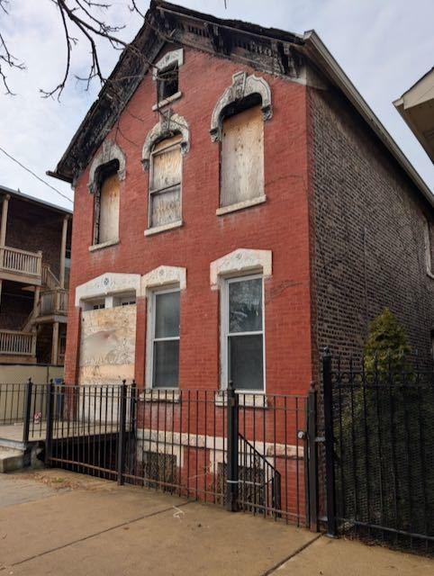 italianate home featuring a fenced front yard and brick siding