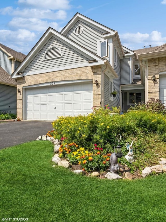 view of front of property with a garage, a front yard, brick siding, and driveway