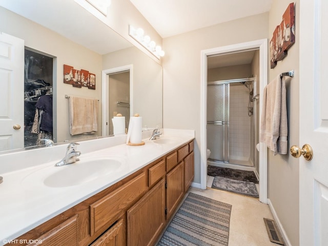 full bath with a stall shower, visible vents, a sink, and double vanity