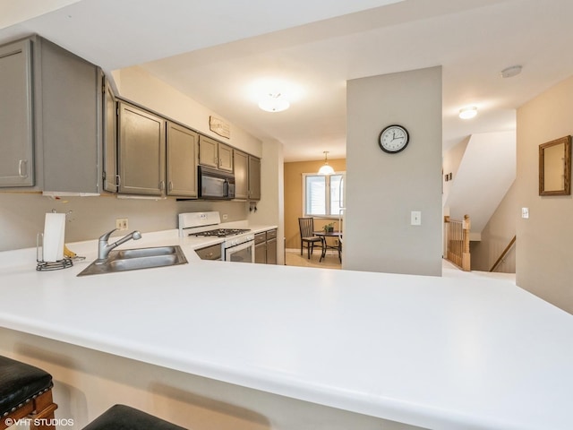 kitchen featuring black microwave, white range with gas stovetop, a sink, light countertops, and gray cabinets