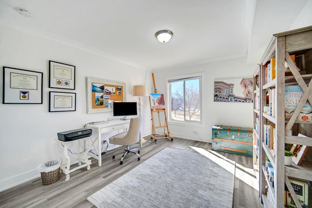 home office featuring light wood-type flooring, baseboards, and crown molding