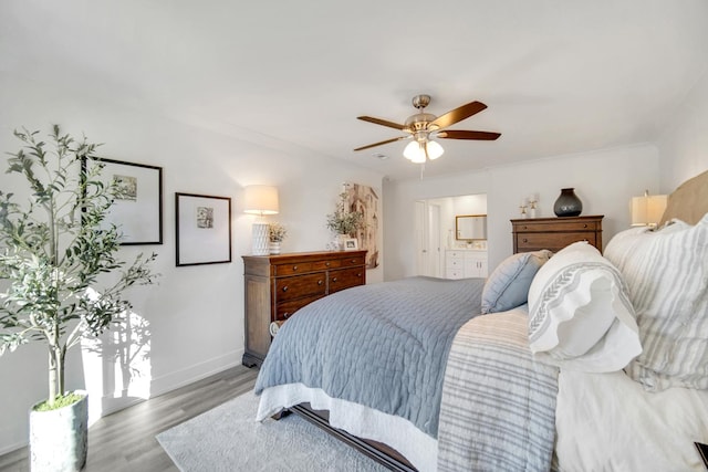 bedroom with light wood finished floors, ceiling fan, baseboards, and ensuite bathroom