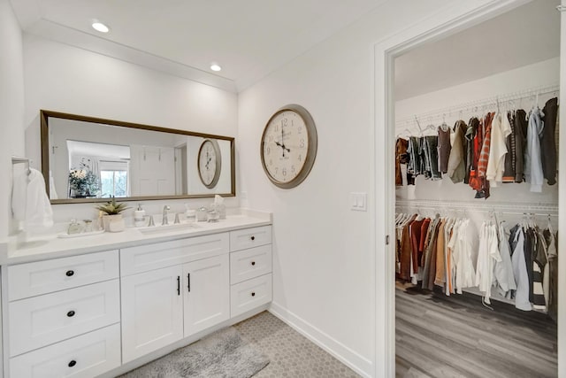 bathroom with recessed lighting, vanity, baseboards, a spacious closet, and ornamental molding