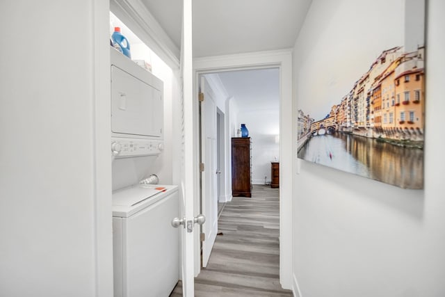 hall with light wood-type flooring, baseboards, and stacked washer / dryer