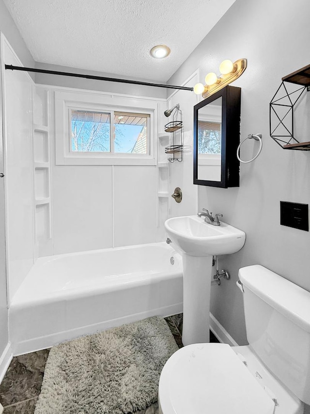 bathroom with toilet, a sink, bathtub / shower combination, and a textured ceiling