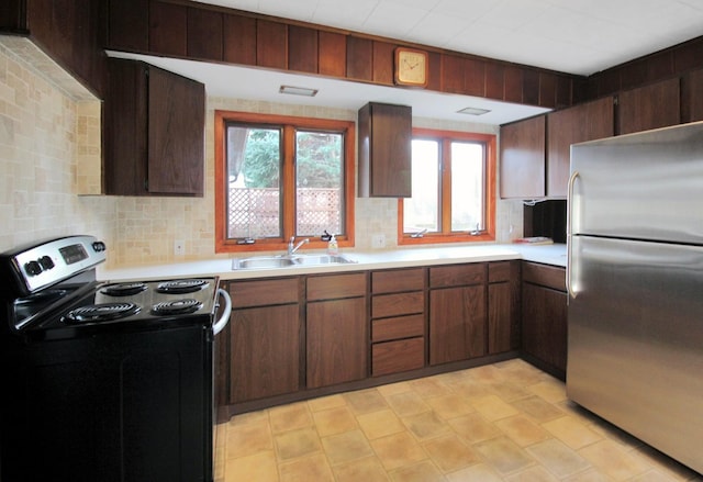 kitchen with a sink, light countertops, electric stove, and freestanding refrigerator