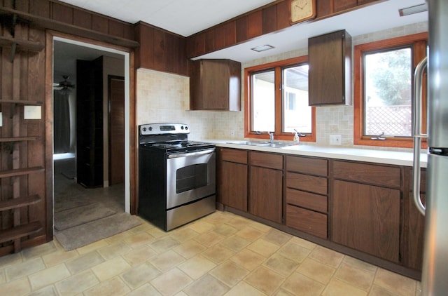 kitchen with a sink, a ceiling fan, light countertops, appliances with stainless steel finishes, and tasteful backsplash