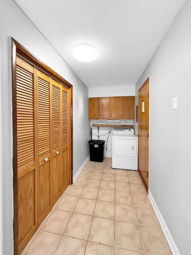 clothes washing area featuring washer / dryer, light tile patterned floors, baseboards, and cabinet space