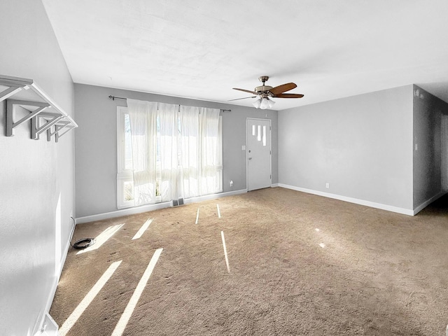 unfurnished living room with visible vents, carpet, a ceiling fan, and baseboards