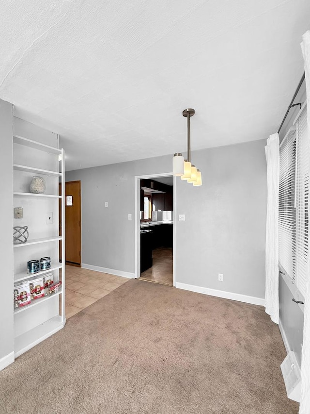 unfurnished living room featuring carpet, a textured ceiling, baseboards, and tile patterned floors