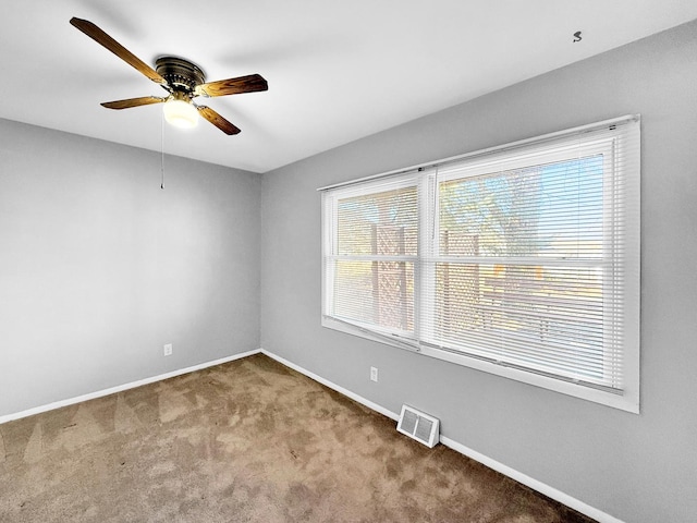 carpeted empty room with visible vents, ceiling fan, and baseboards