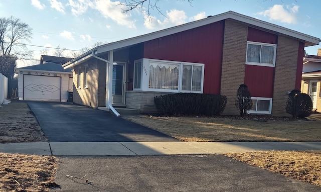 view of property exterior with a garage, an outbuilding, brick siding, and driveway