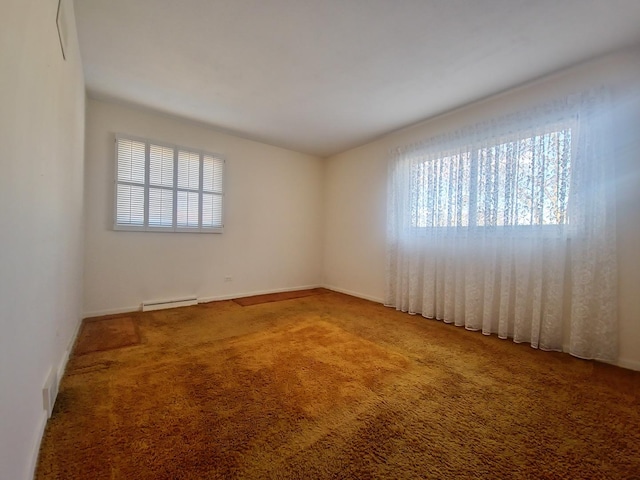 carpeted empty room with a healthy amount of sunlight and a baseboard heating unit