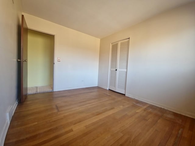 unfurnished bedroom featuring a closet, wood finished floors, and baseboards