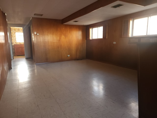 below grade area featuring wood walls, visible vents, and tile patterned floors