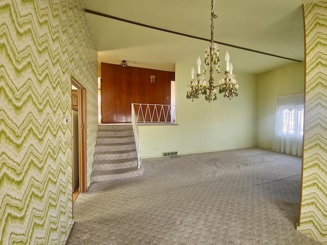 spare room with carpet floors, a chandelier, visible vents, and stairway