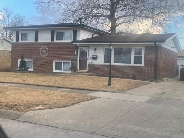 tri-level home featuring brick siding and a front lawn