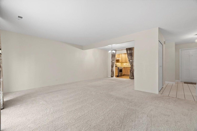 spare room featuring carpet floors and a notable chandelier