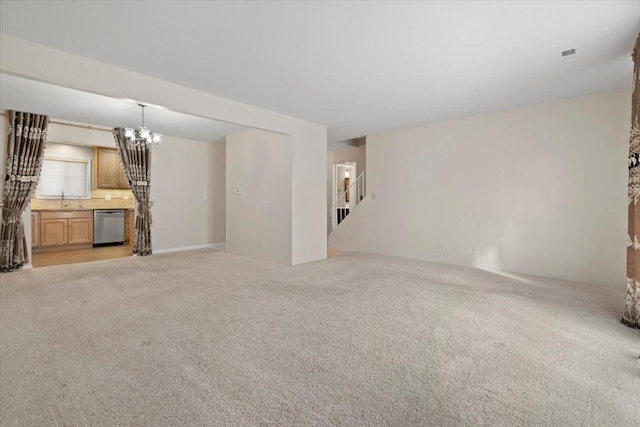 unfurnished living room with stairs, an inviting chandelier, and light colored carpet