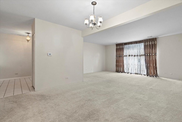 carpeted empty room featuring an inviting chandelier and tile patterned flooring