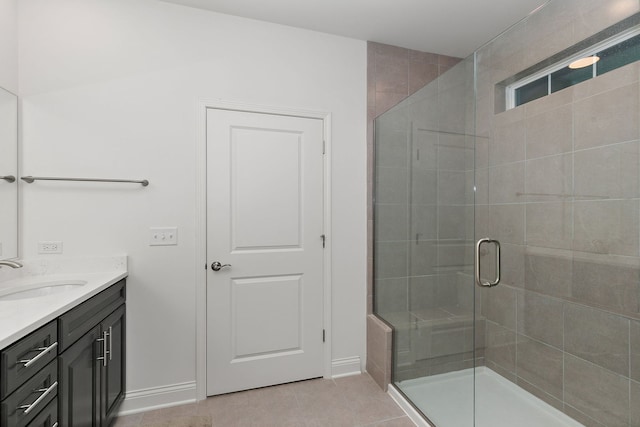 bathroom with a stall shower, tile patterned flooring, vanity, and baseboards