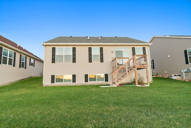 back of property with stairs, a yard, and a shingled roof