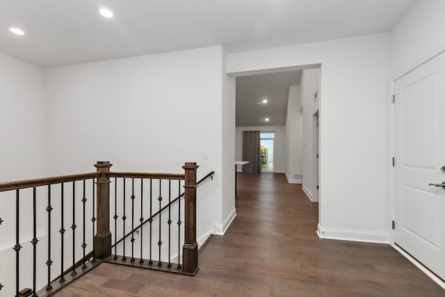 corridor with dark wood-style floors, recessed lighting, baseboards, and an upstairs landing