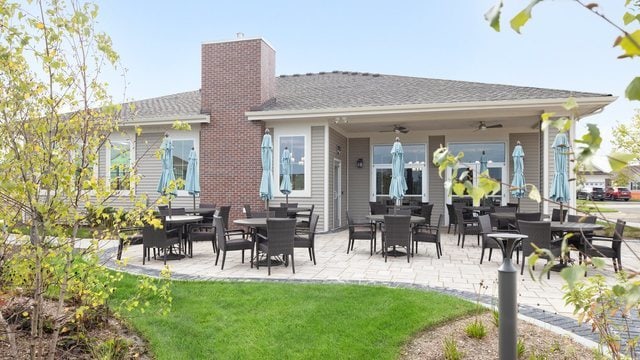 back of property with a patio area, ceiling fan, a chimney, and a lawn