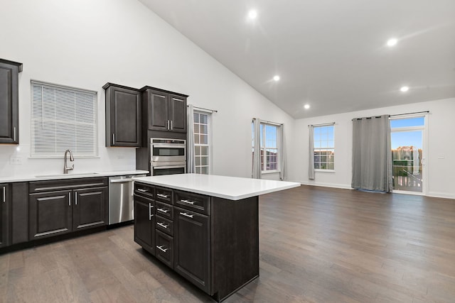 kitchen with a sink, light countertops, appliances with stainless steel finishes, a center island, and dark wood-style floors