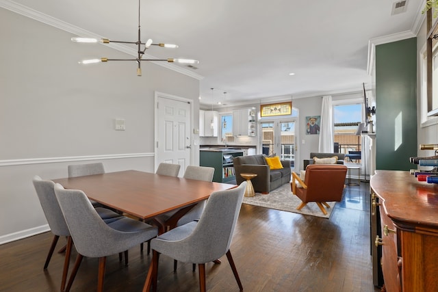 dining space with a chandelier, visible vents, baseboards, ornamental molding, and dark wood finished floors