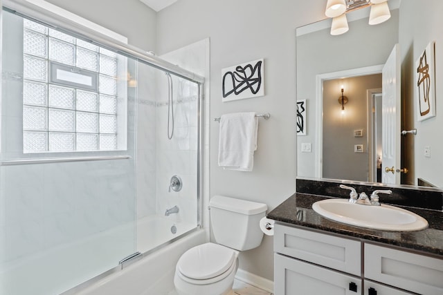 full bathroom with toilet, baseboards, bath / shower combo with glass door, and vanity