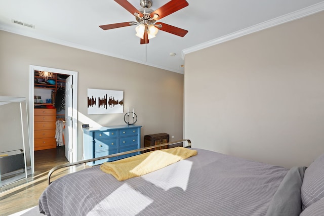 bedroom featuring wood finished floors, visible vents, a spacious closet, a closet, and crown molding