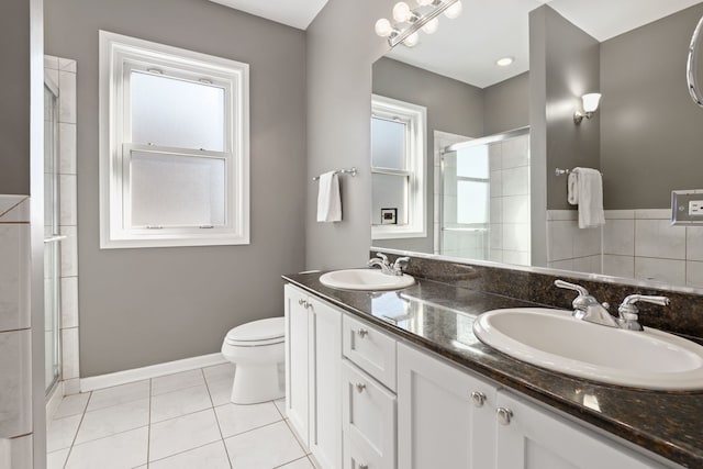 bathroom featuring tile patterned flooring, a sink, toilet, and a shower stall