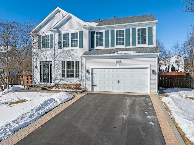 view of front facade featuring aphalt driveway, fence, and an attached garage