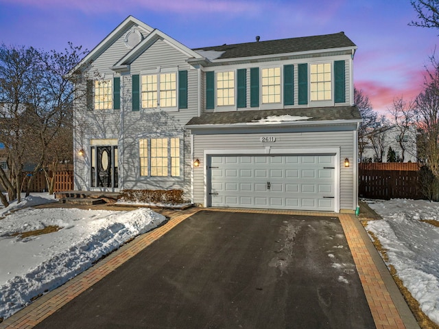 view of front of property with driveway, an attached garage, and fence