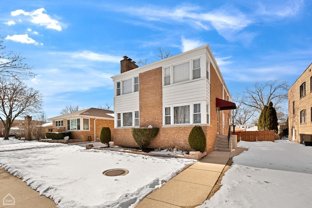 view of front of house featuring brick siding and a chimney