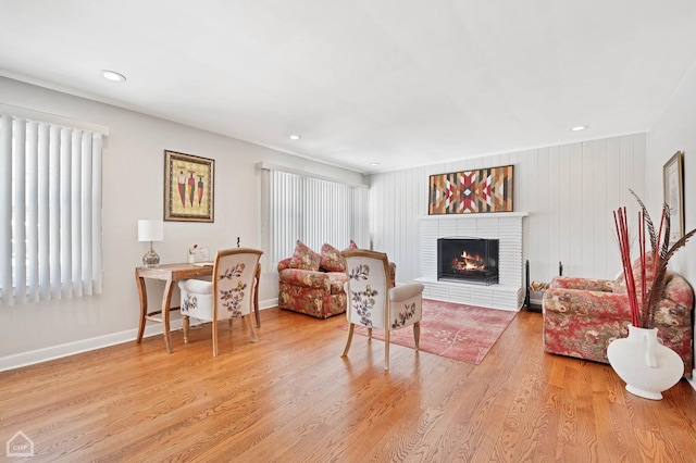 living room featuring light wood-style flooring, a fireplace, baseboards, and recessed lighting